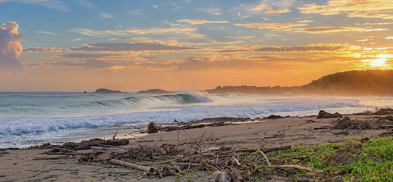 Waves along the beach beneath a golden sky