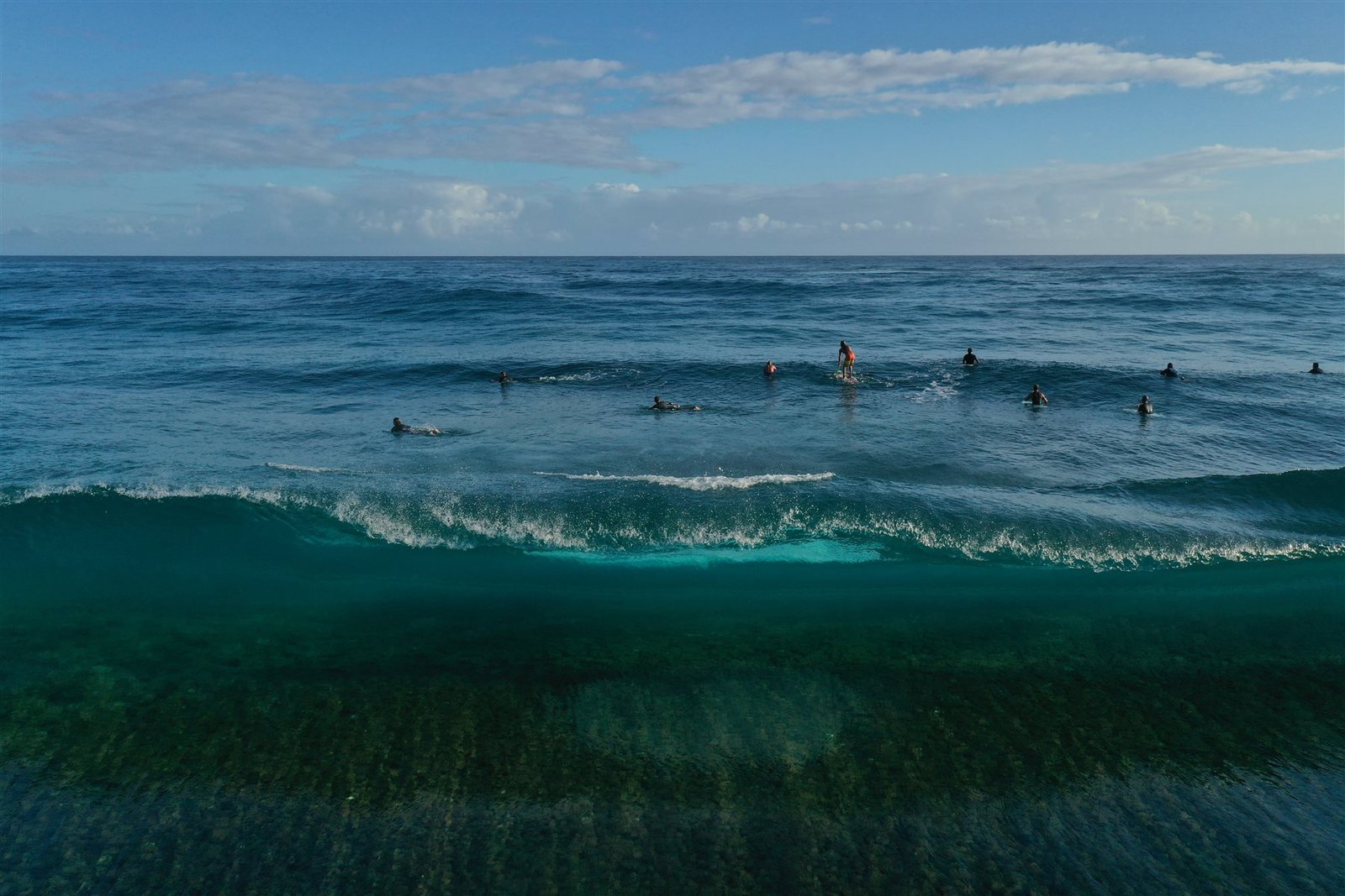 Aerial view of surfers waiting for waves in clear water
