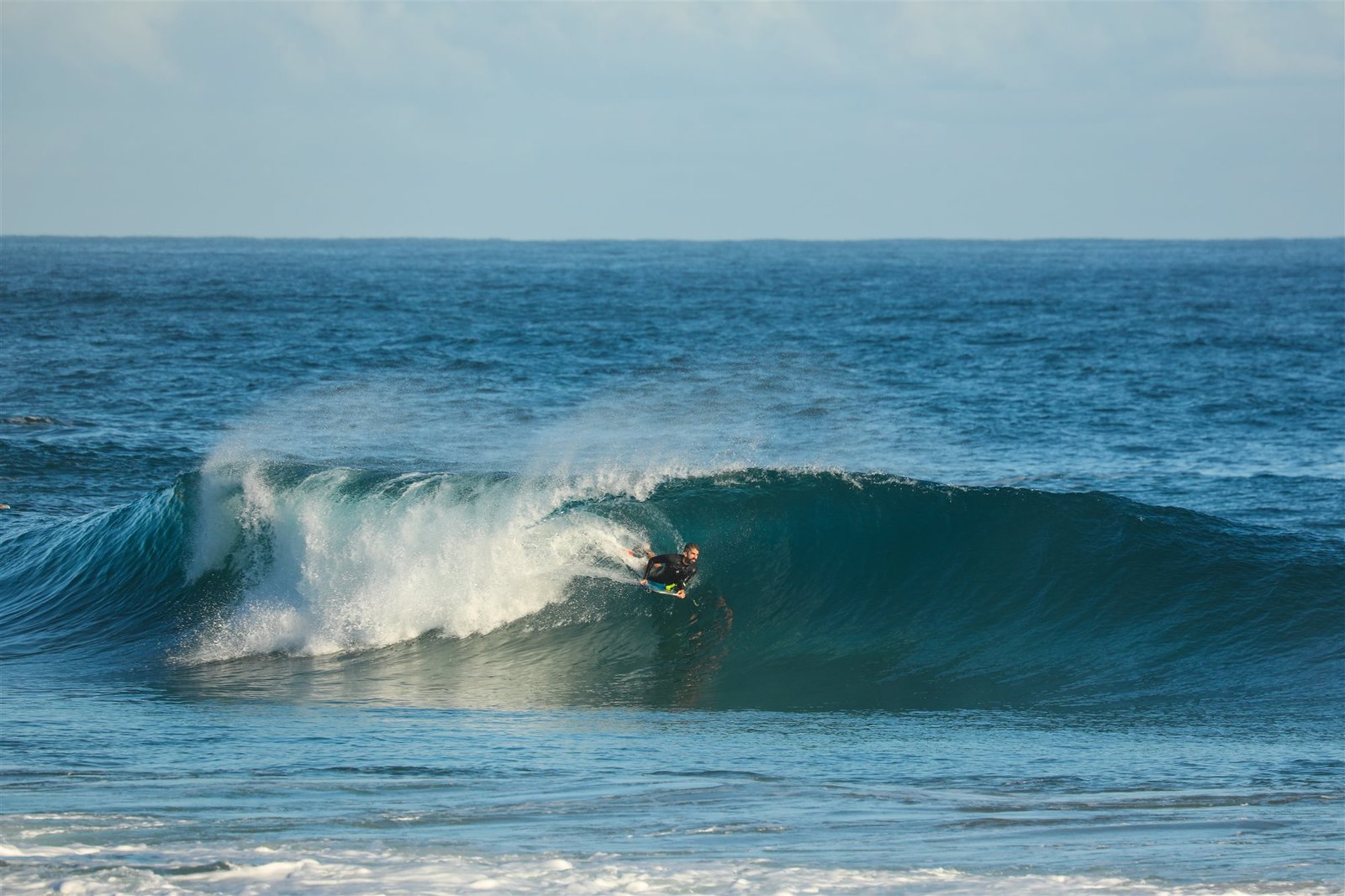 Bodyboarder riding a wave with the open ocean in the background